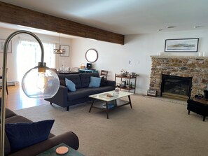 Ein Wohnzimmer mit Kamin aus Stein, einer Couch, einem Couchtisch und einer Pendelleuchte.
