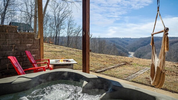 Ein Whirlpool mit Blick auf ein Tal, rote Stühle und eine Hängeschaukel.
