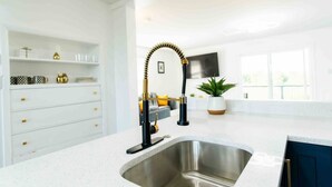 A modern kitchen with a stainless steel sink, white cabinetry, and a gold faucet.