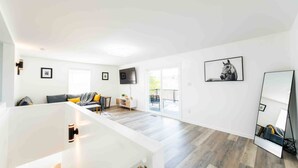 A spacious living area with a sofa, a TV, and a balcony.