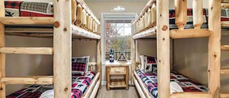 A bunk bed room with a desk and window, featuring a 'Adventure' sign and a 'Hire More, Work Less' sign.