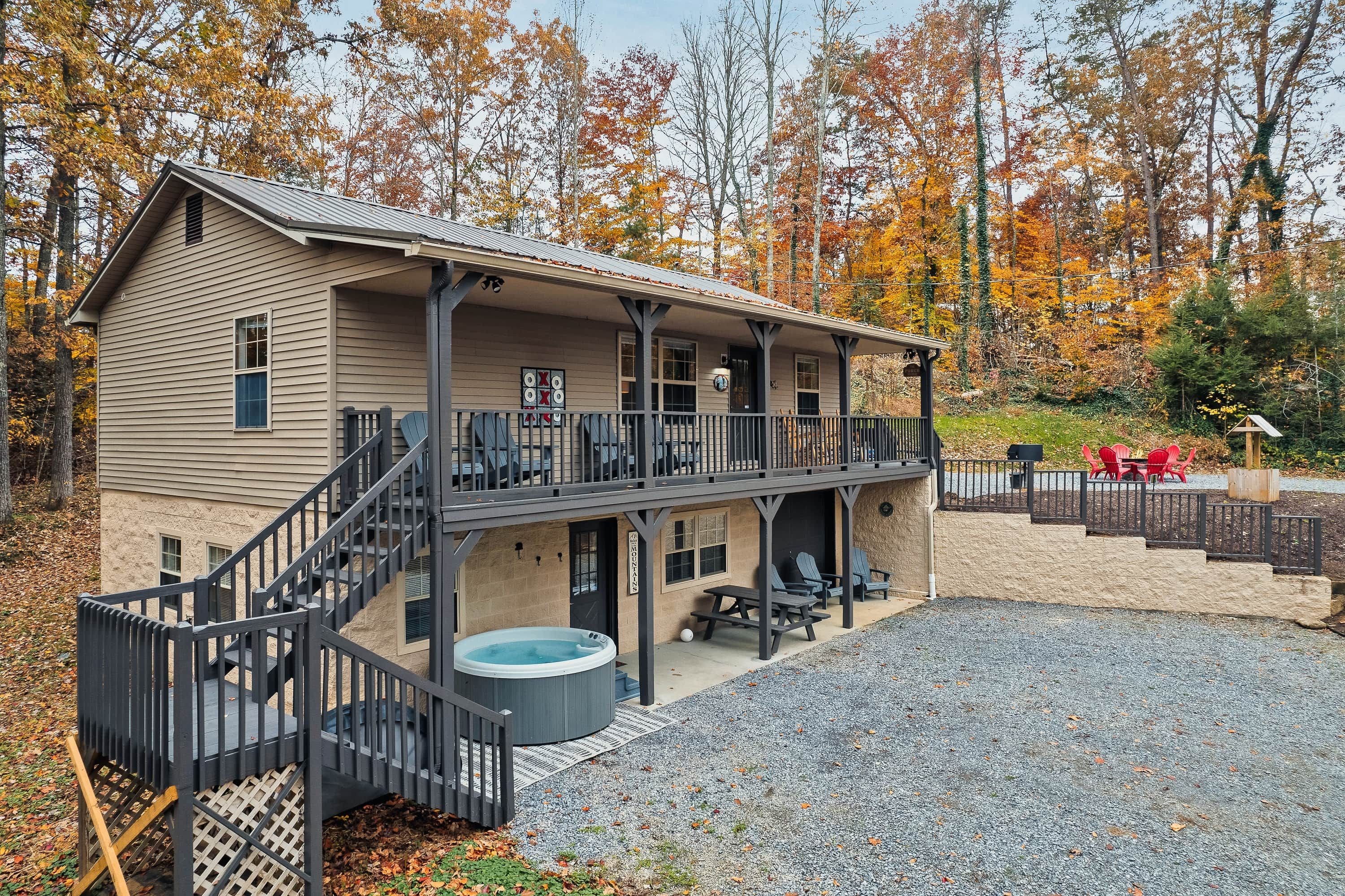A two-story lodge with a balcony, a hot tub, and a covered patio area.