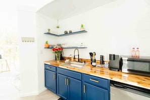 Une cuisine moderne avec des meubles bleus, un plan de travail en bois, un évier encastré et un four à micro-ondes.