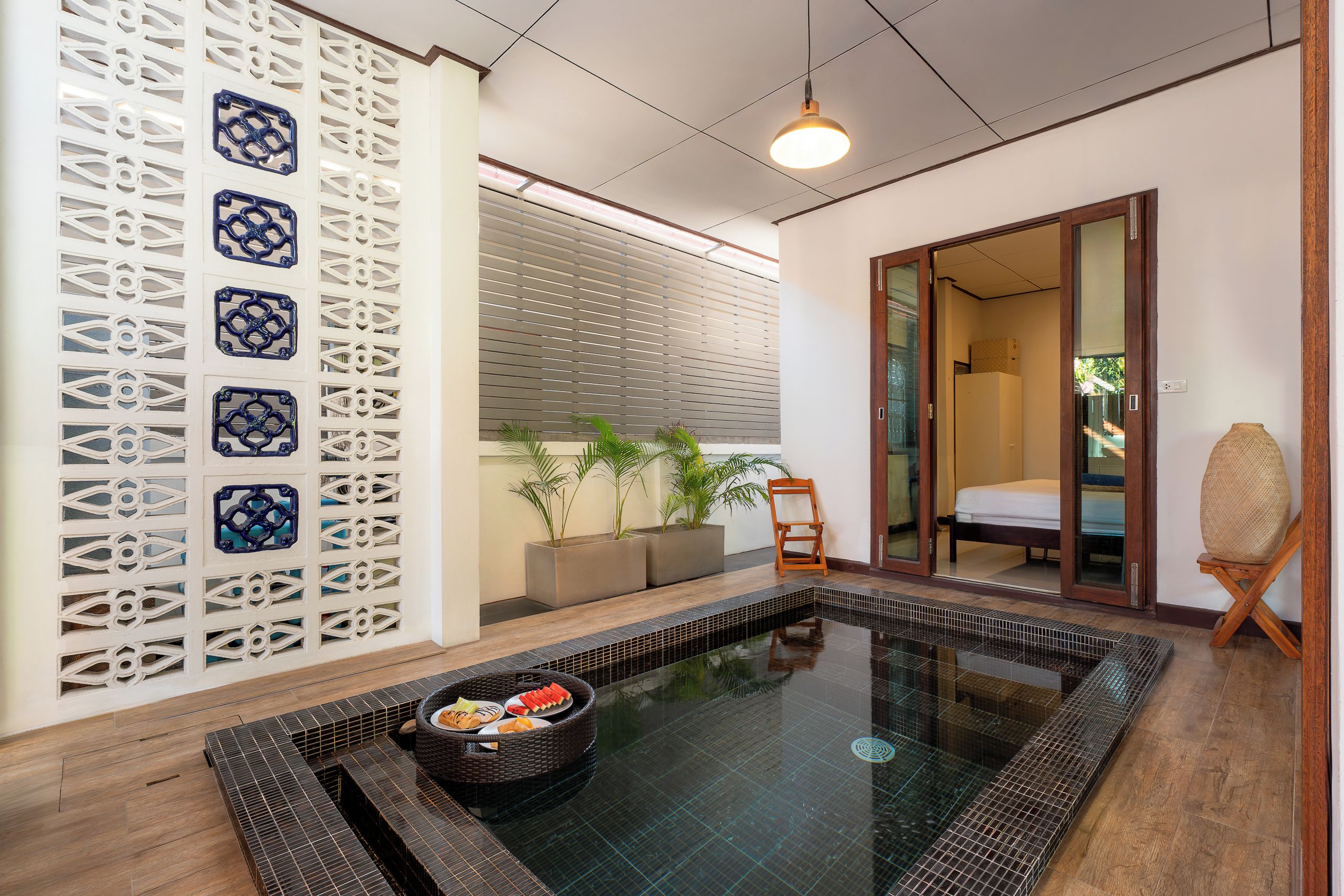 A modern bathroom with a glass shower enclosure, a wooden chair, and a small table with fruit.