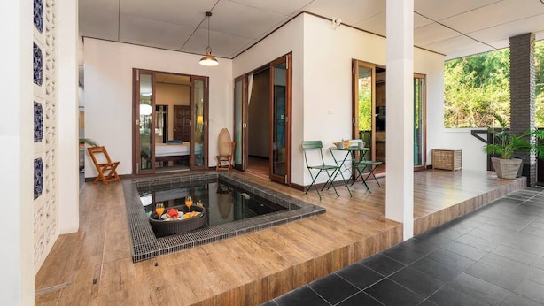 Camera d'hotel moderna con piscina privata, pavimento in legno e zona pranzo con posti a sedere all'aperto.