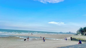 Una spiaggia con persone, cielo sereno e montagne in lontananza.
