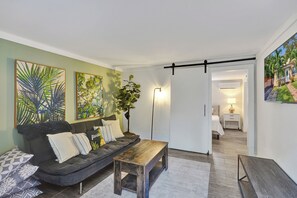 Ein modernes Wohnzimmer mit einer Couch, einem Couchtisch und einem Gemälde an der Wand.