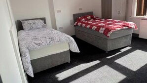 A bedroom with two beds, a wardrobe, and a radiator. - Spacious Wakefield Getaway 3br (Wrenthorpe)