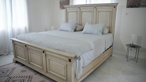 A bedroom with a large bed, a bedside table, and a nightstand. - Casa de Paz
House of Peace (Little London)