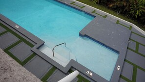 A swimming pool with a tiled edge, a diving board, and a small grassy area with a sign indicating a 3 ft depth. - Casa de Paz
House of Peace (Little London)