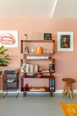 Ein Wohnzimmer mit Bücherregal, Plattenspieler, kleinem Tisch und einer Pflanze.