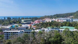 A coastal town with a mix of residential and commercial buildings, including a large stadium and a colorful festival area. - Beach 3 Mins Fantasea Resort Kamala C190 (Tambon Kamala)