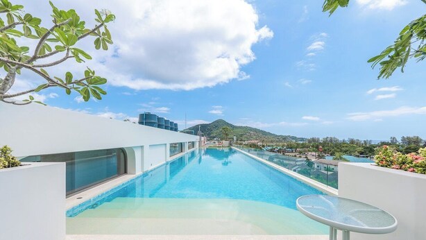 A rooftop pool with a clear view of a mountain, surrounded by white walls and greenery. - Beach 3 Mins Fantasea Resort Kamala C190 (Tambon Kamala)