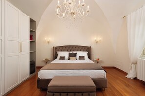 Ein Schlafzimmer mit einem großen Bett, einer Chandelüster, weißen Wänden und einem Holzboden.