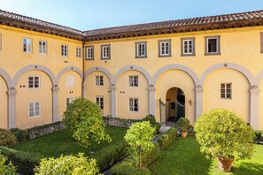 A yellow building with arched windows and a tiled roof, surrounded by a well-maintained garden. - *Elegance in a 1500s Palazzo* · Lucca Centro (Lucca)