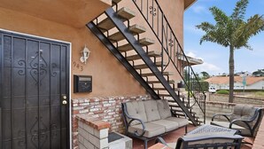 Un patio con pared de ladrillo, escalera de metal y mobiliario exterior.
