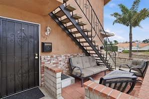 A patio with a brick wall, a metal staircase, and outdoor furniture. - Delightful Ocean Breeze 1-bedroom apartment in San Pedro (Los Angeles)