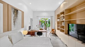 Moderni hotellihuone, jossa on sänky, työpöytä, televisio ja näkymä ulos.