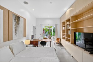 Ein modernes Hotelzimmer mit Bett, Schreibtisch, Fernseher und Blick ins Freie.