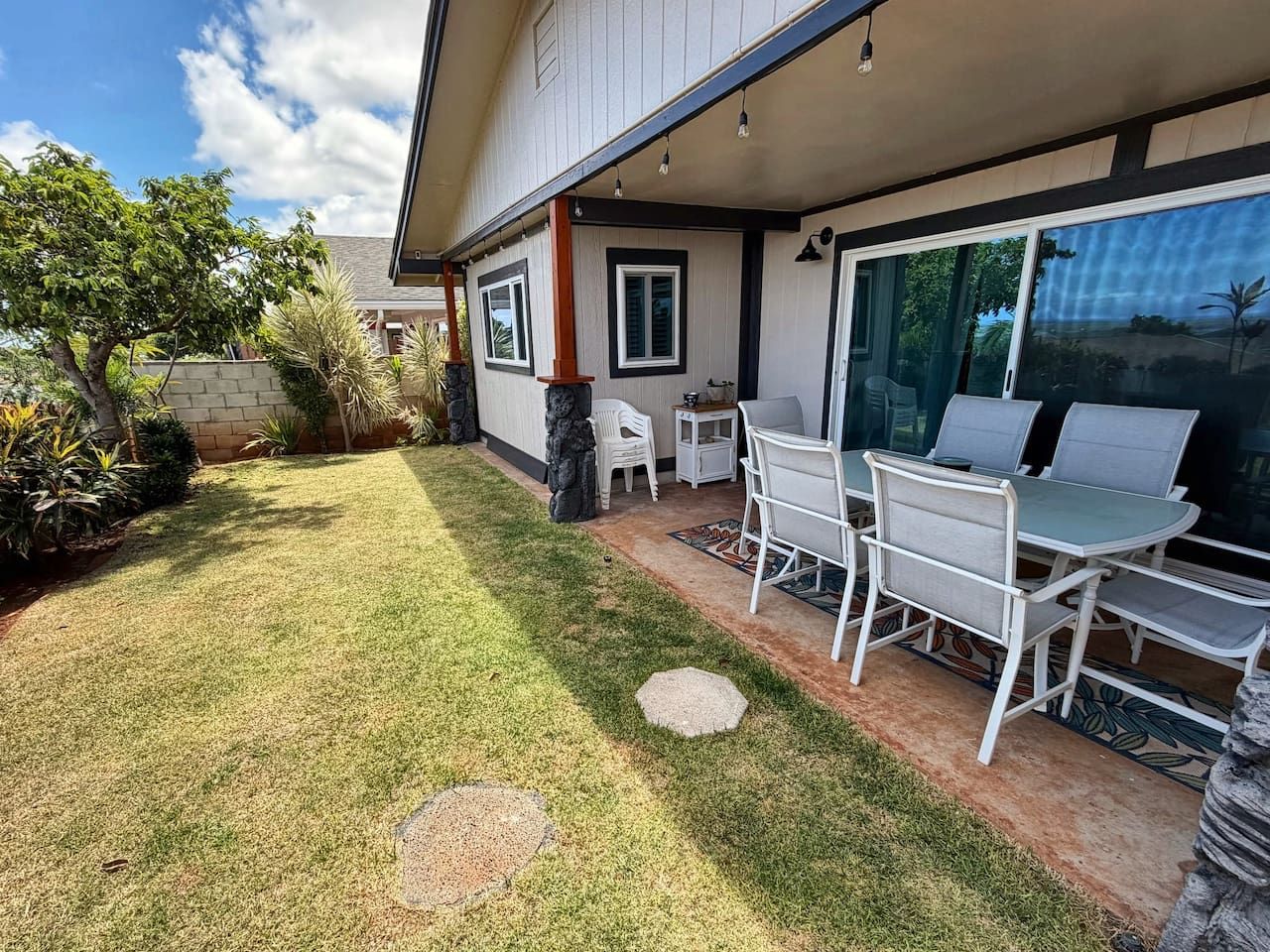 Una propiedad residencial con un patio que cuenta con una mesa y sillas, césped y una casa con porche cubierto.