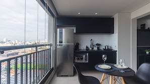 A balcony with a view of the city, a kitchen with modern appliances, and a dining area with a table and chairs. - Excellent Studio in S o Paulo - Sp-a1107 (São Paulo)