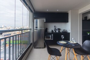 A balcony with a view of the city, a kitchen with modern appliances, and a dining area with a table and chairs. - Excellent Studio in S o Paulo - Sp-a1107 (São Paulo)
