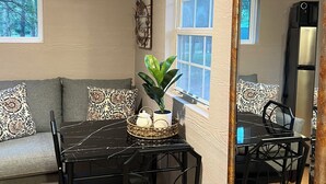 A dining area with a table, chairs, a potted plant, and a mirror.