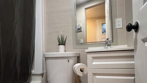 A bathroom with a toilet, sink, mirror, and shower curtain.