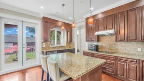 A modern kitchen with granite countertops, wooden cabinets, and pendant lighting.