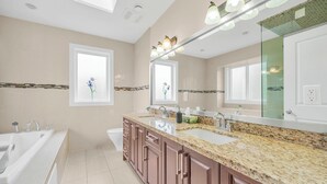 A modern bathroom with a large mirror, two sinks, a bathtub, and a window with a flower decoration.