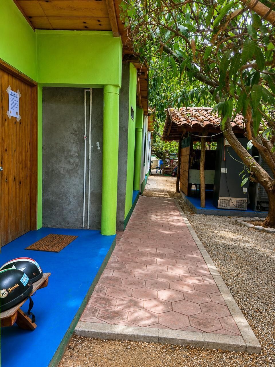A corridor with a blue mat, a green wall, and a tiled roof structure.