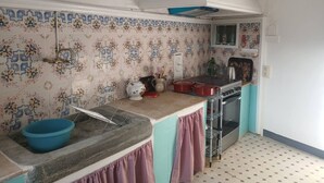 Uma cozinha com ladrilhos estampados, pia, fogão e janela.