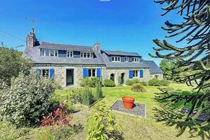 Ein Haus aus Stein mit Garten, einem roten Blumentopf und einem Farne.