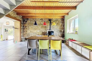 Ein Essbereich mit Steinwand, Holzbalkendecke und einem Tisch mit Stühlen.