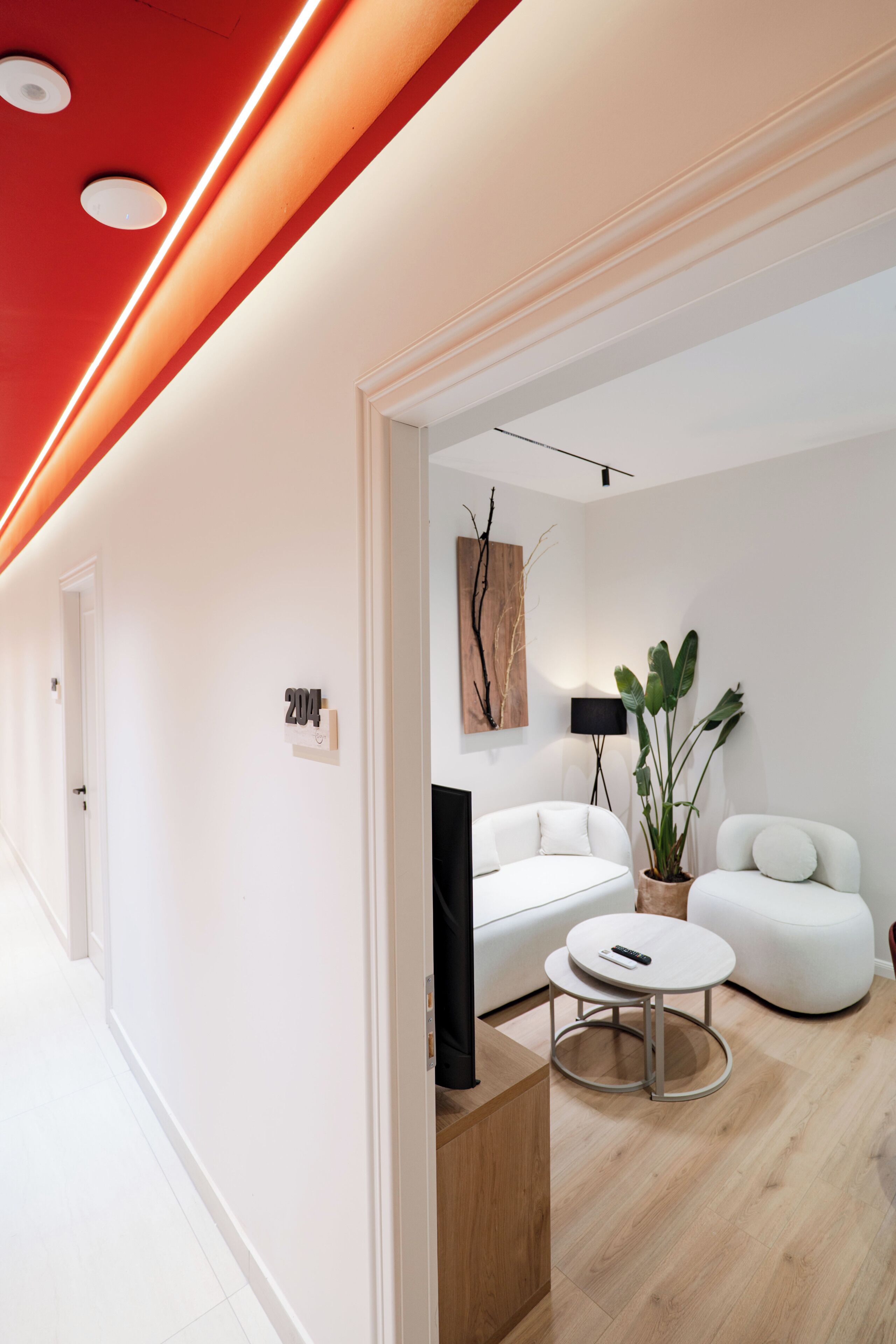 Een moderne woonkamer met een witte bank, een ronde salontafel en een potplant.