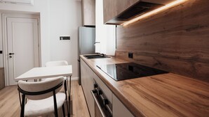 A modern kitchen with a wooden countertop, built-in oven, and a white dining table with chairs.