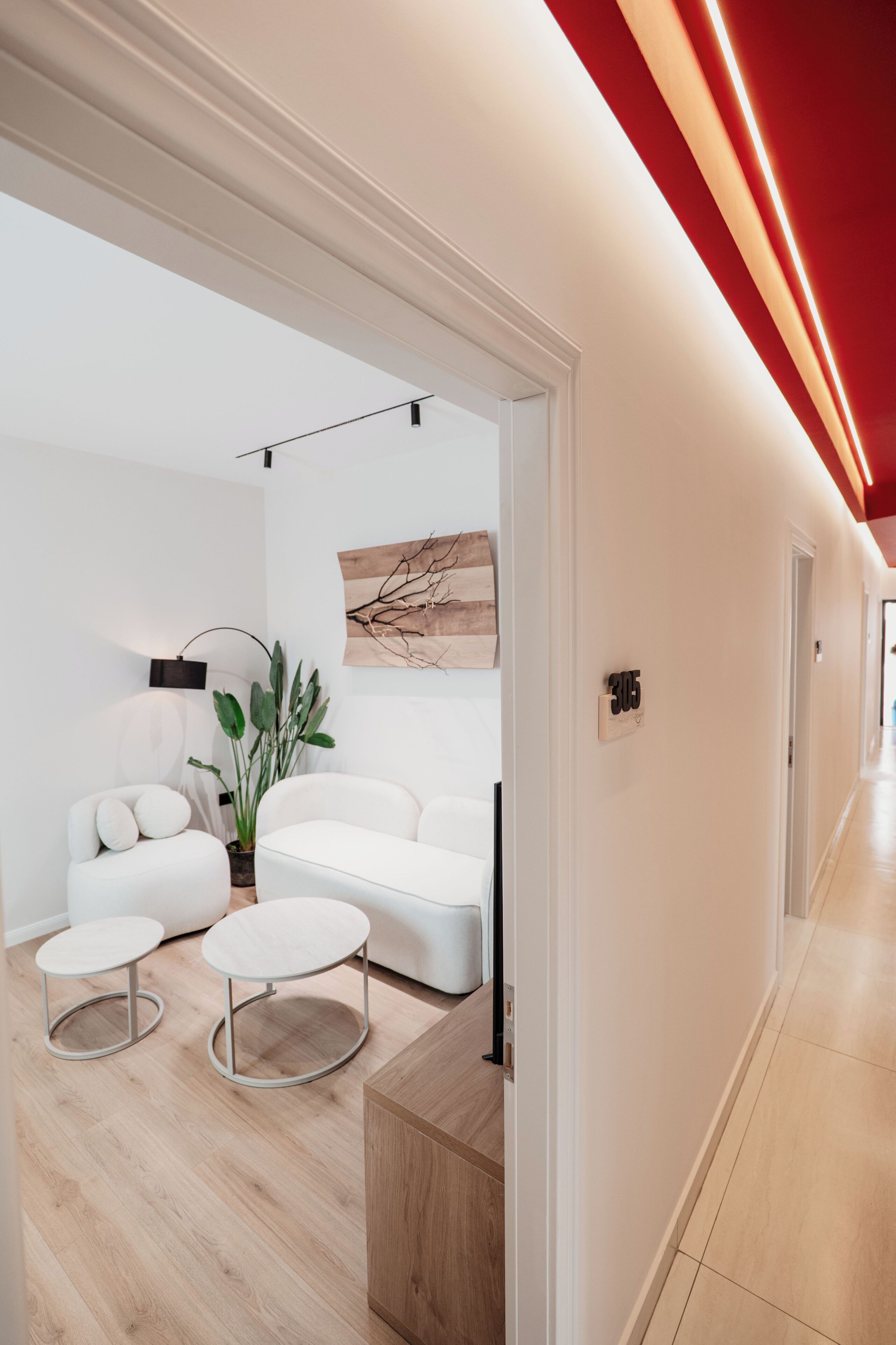 Un interior moderno con un conjunto de sofá blanco, mesas redondas y un aparador de madera.