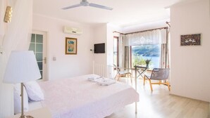 A bedroom with a bed, a ceiling fan, a window with curtains, a chair, and a view of the outdoors. - Masal Tatil Evi  (Marmaris)