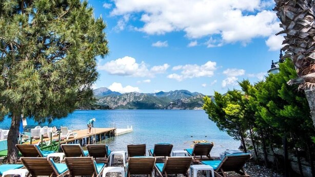 A lakeside resort with lounge chairs and a dock. - Masal Tatil Evi  (Marmaris)