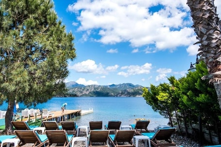 A lakeside resort with lounge chairs and a dock.. Masal Tatil Evi