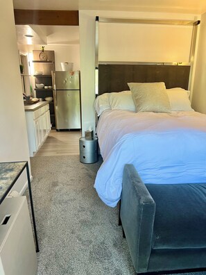 Ein Hotelzimmer mit Bett, Nachttisch und einer Küchenzeile.