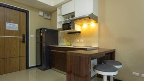 A compact kitchen with a microwave, refrigerator, and wooden cabinets. - MBC MaiKhao 1BR Condo•Poolside•Walk 2 Beach C194 (Tambon Mai Khao)