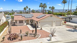 A single-story house with a tiled roof, solar panels, a garage, and a cactus garden. - South Palm Desert Home with Private Pool, 3-Car Garage & Close to El Paseo (Palm Desert)