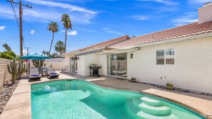 A swimming pool with a sunken center, a patio with lounge chairs, and a covered outdoor area with a grill. - South Palm Desert Home with Private Pool, 3-Car Garage & Close to El Paseo (Palm Desert)