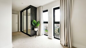 A modern room with a large sliding glass door, a potted plant, and a view of the outside. - 4-Guest North London | Piccadilly Line into Zone 1 (Barnet)