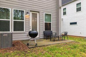 Une maison dotée d’un patio couvert, d’un barbecue et de meubles pour se détendre à l’extérieur.