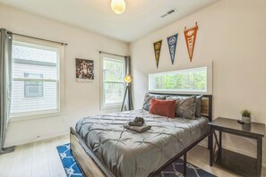 A bedroom with a bed, a desk, and two windows. There are three pennants on the wall. - Spacious King Ste Pool Table, Mins to NoDa & UPTWN! (Charlotte)