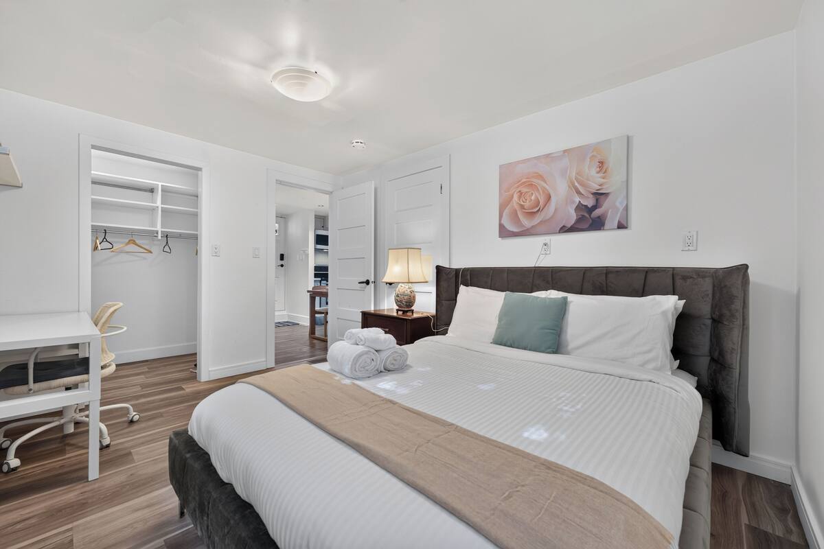 Un dormitorio moderno con cama, mesita de noche, lámpara y vestidor.