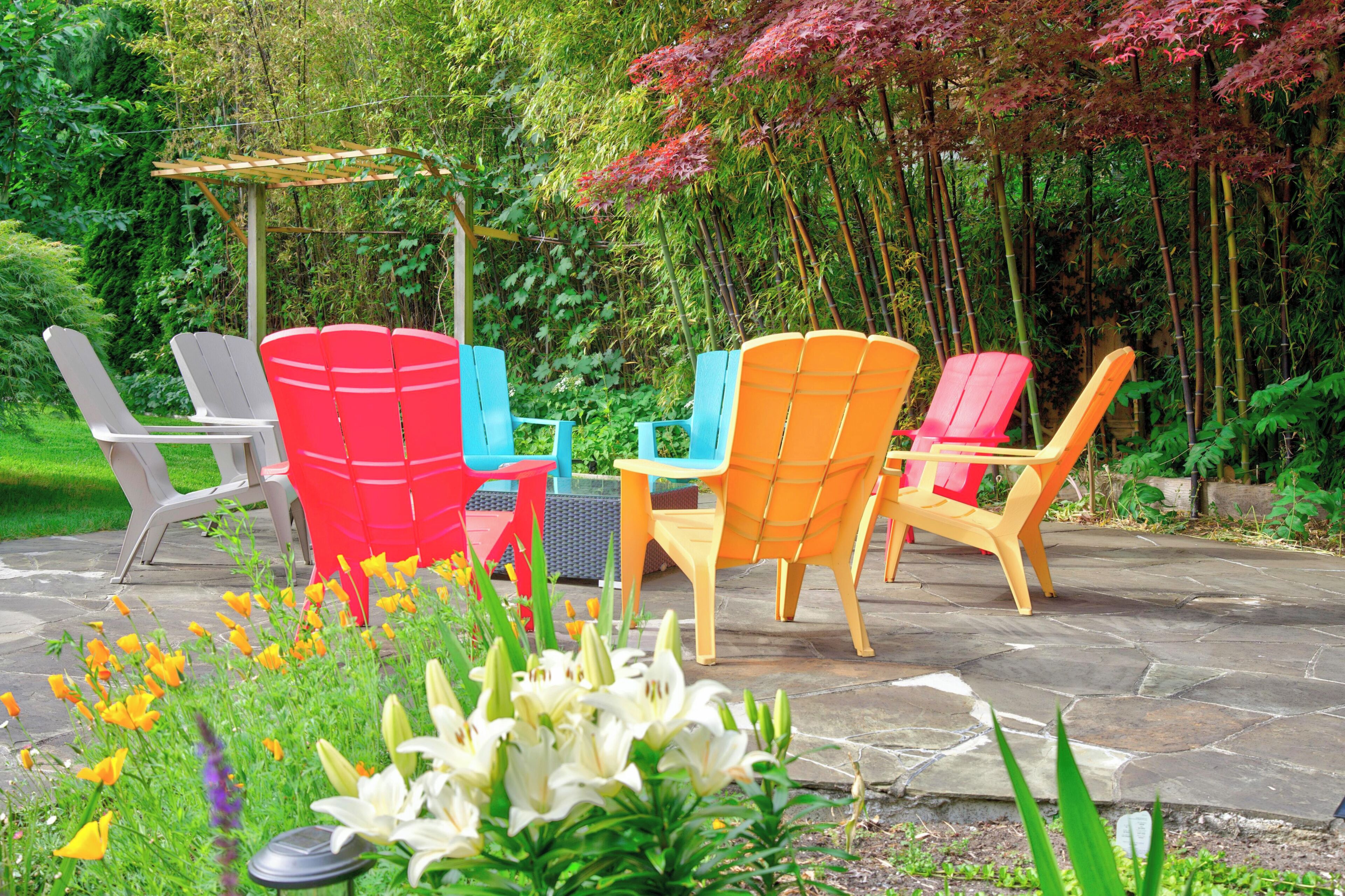 Outdoor seating with chairs and a table, surrounded by greenery and flowers.