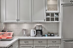 A kitchen with grey cabinets, a coffee maker, a kettle, and a sink. - Tranquil Garden Level Retreat near UBC & Airport (Vancouver)